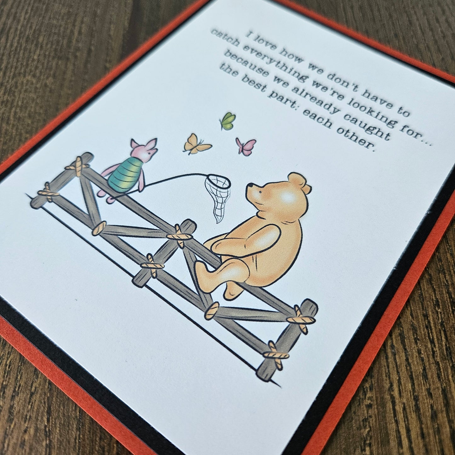 Handmade Winnie the Pooh friendship card featuring a classic storybook illustration of Pooh Bear and Piglet sitting together on a rustic wooden fence watching butterflies, finished with layered cardstock frames.