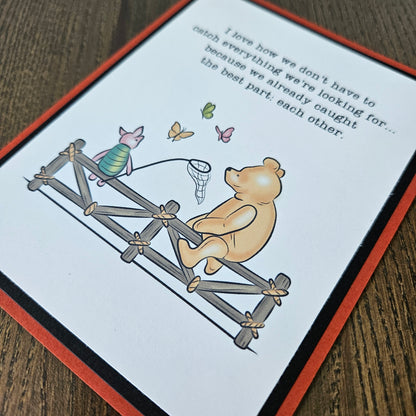 Handmade Winnie the Pooh friendship card featuring a classic storybook illustration of Pooh Bear and Piglet sitting together on a rustic wooden fence watching butterflies, finished with layered cardstock frames.
