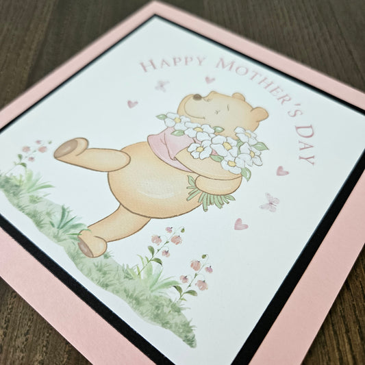 Handmade Winnie the Pooh Mother's Day card holding flowers on a pink border