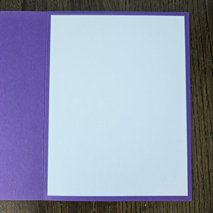 Purple card with a white center on a wooden surface