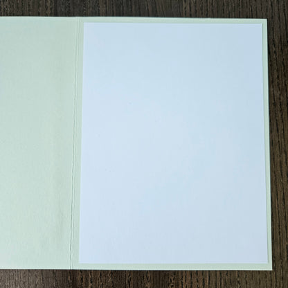 Two-tone card with white top and light green bottom on a wooden surface