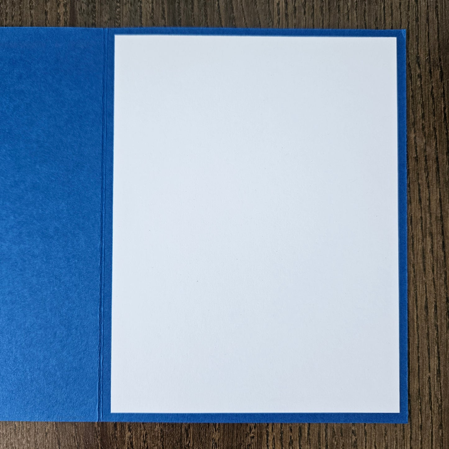 Blue pocket folder with a white sheet of paper inside on a wooden surface