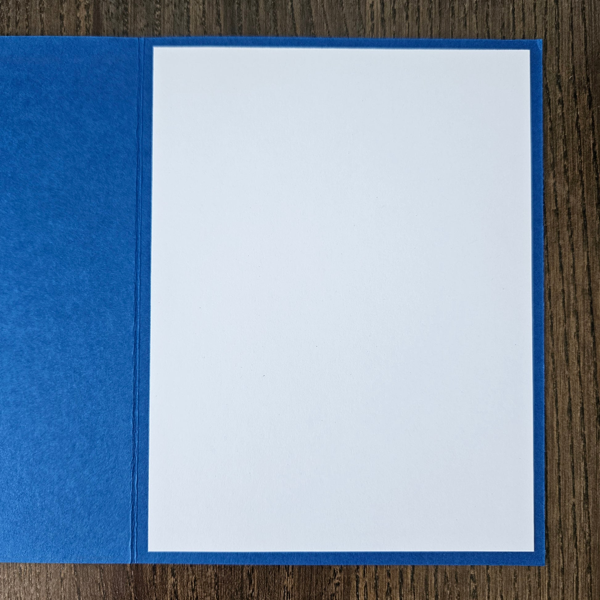 Blue pocket folder with a white sheet of paper inside on a wooden surface