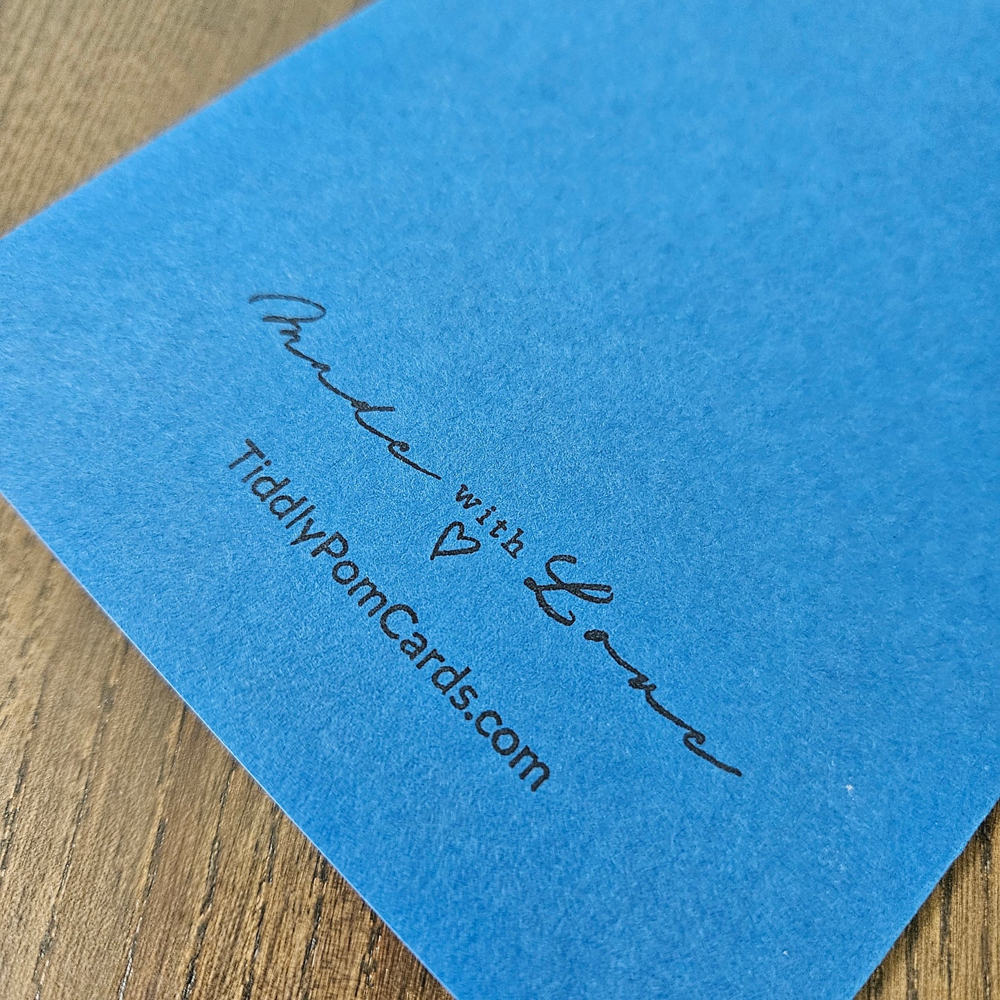 Blue card with 'Made with Love' and TiddlyPomCards.com text on a wooden surface