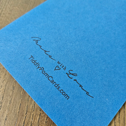 Blue card with 'Made with Love' and TiddlyPomCards.com text on a wooden surface