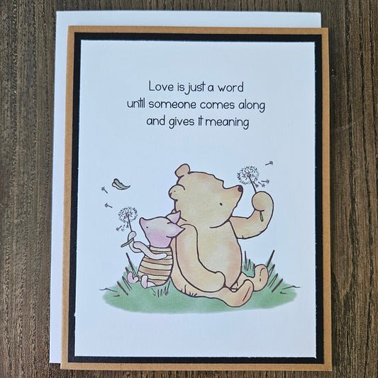 Card with cartoon dog and cat holding hands and text on a wooden surface