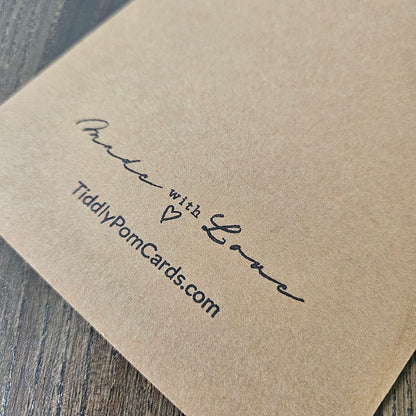 Kraft paper card with 'Made with Love' and 'TiddlyPomCards.com' text on a wooden surface