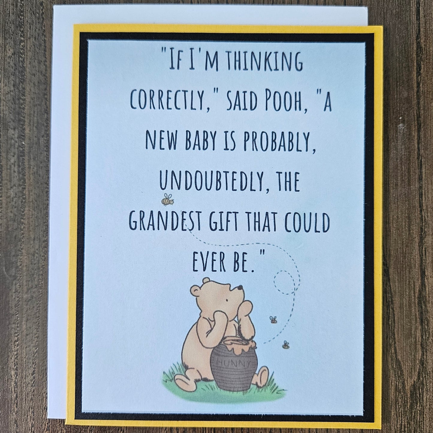 Greeting card with Winnie the Pooh illustration and text on a wooden surface