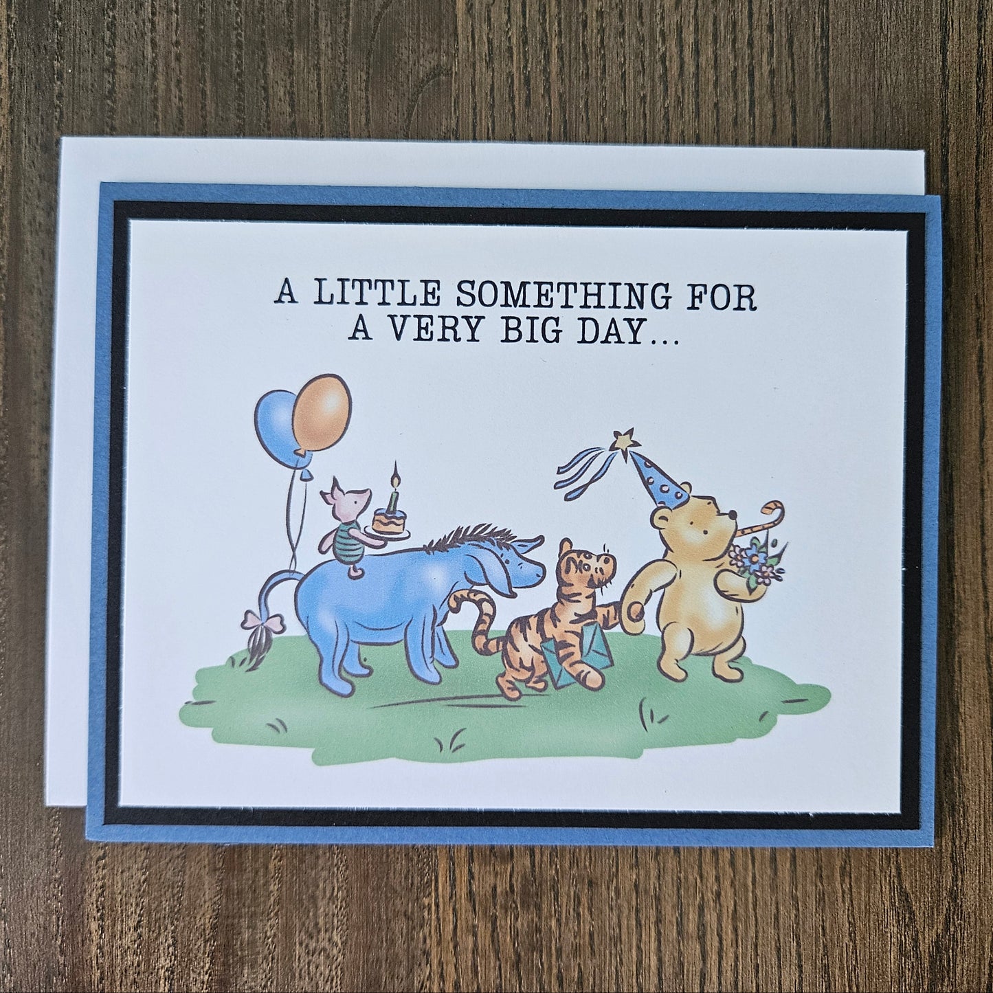 Greeting card with cartoon animals and birthday-themed text on a wooden surface