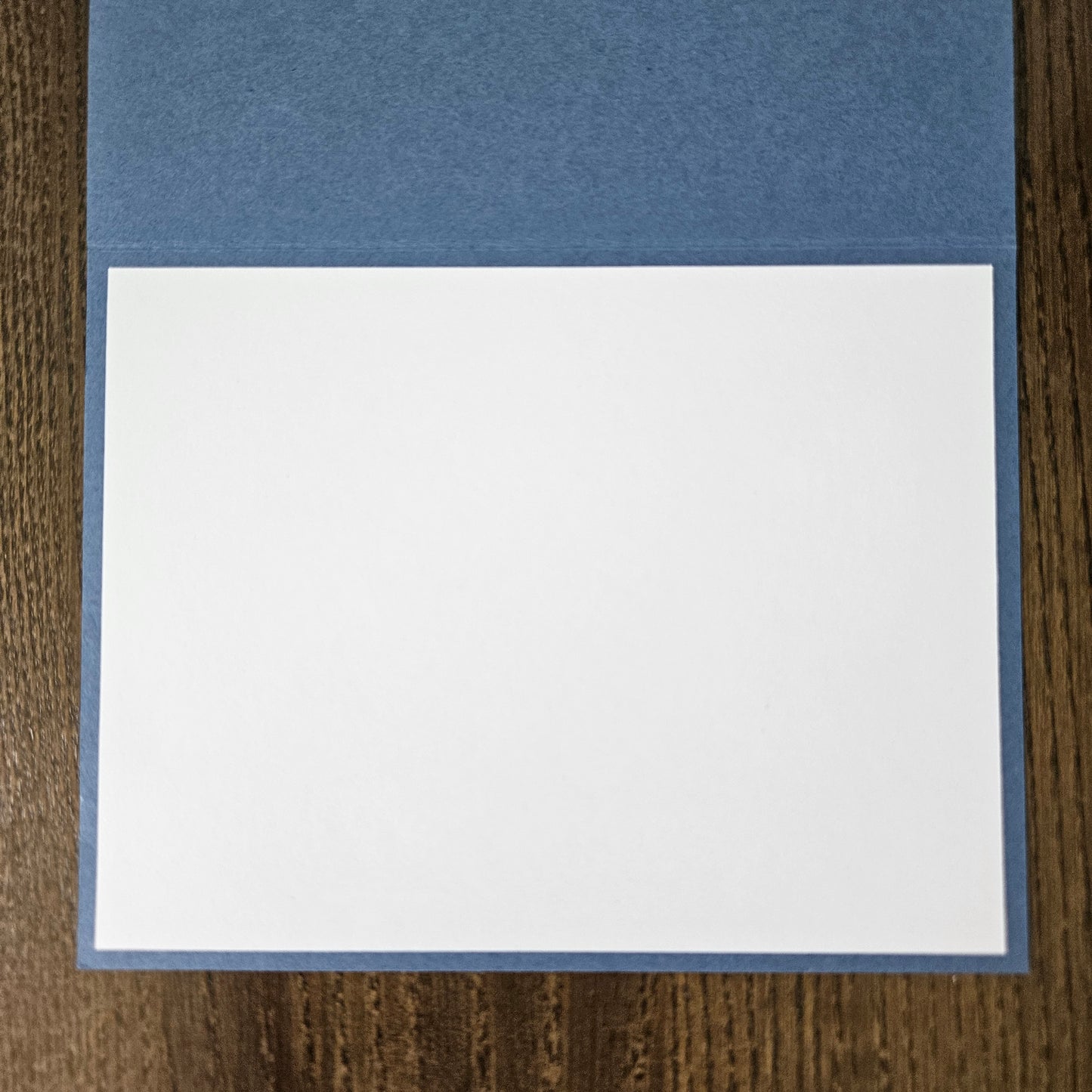 Two pieces of paper, one blue and one white, on a wooden surface.