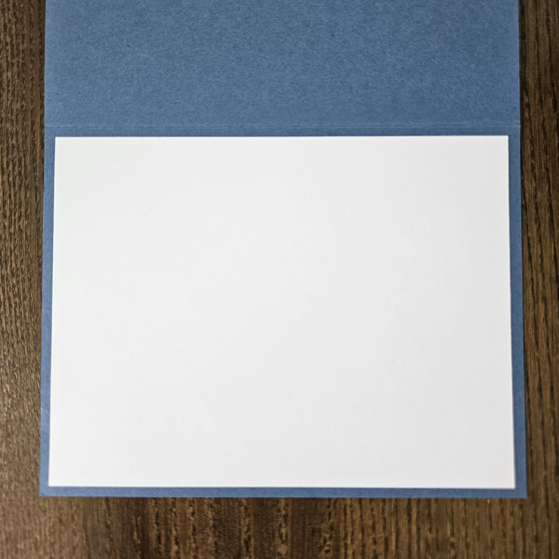 Two pieces of paper, one blue and one white, on a wooden surface.