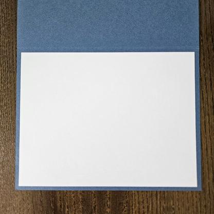 Two pieces of paper, one blue and one white, on a wooden surface.