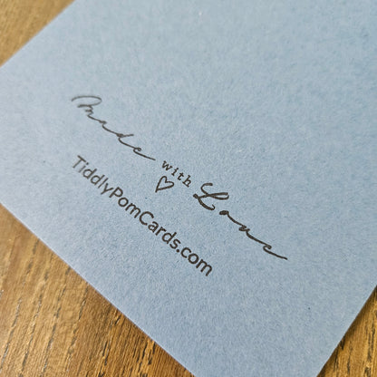 Light blue card with 'Made with Love' and TiddlyPomCards.com text on a wooden surface
