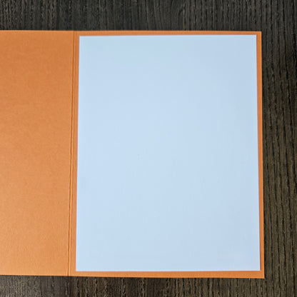 Notebook with light blue cover and brown back on a wooden surface