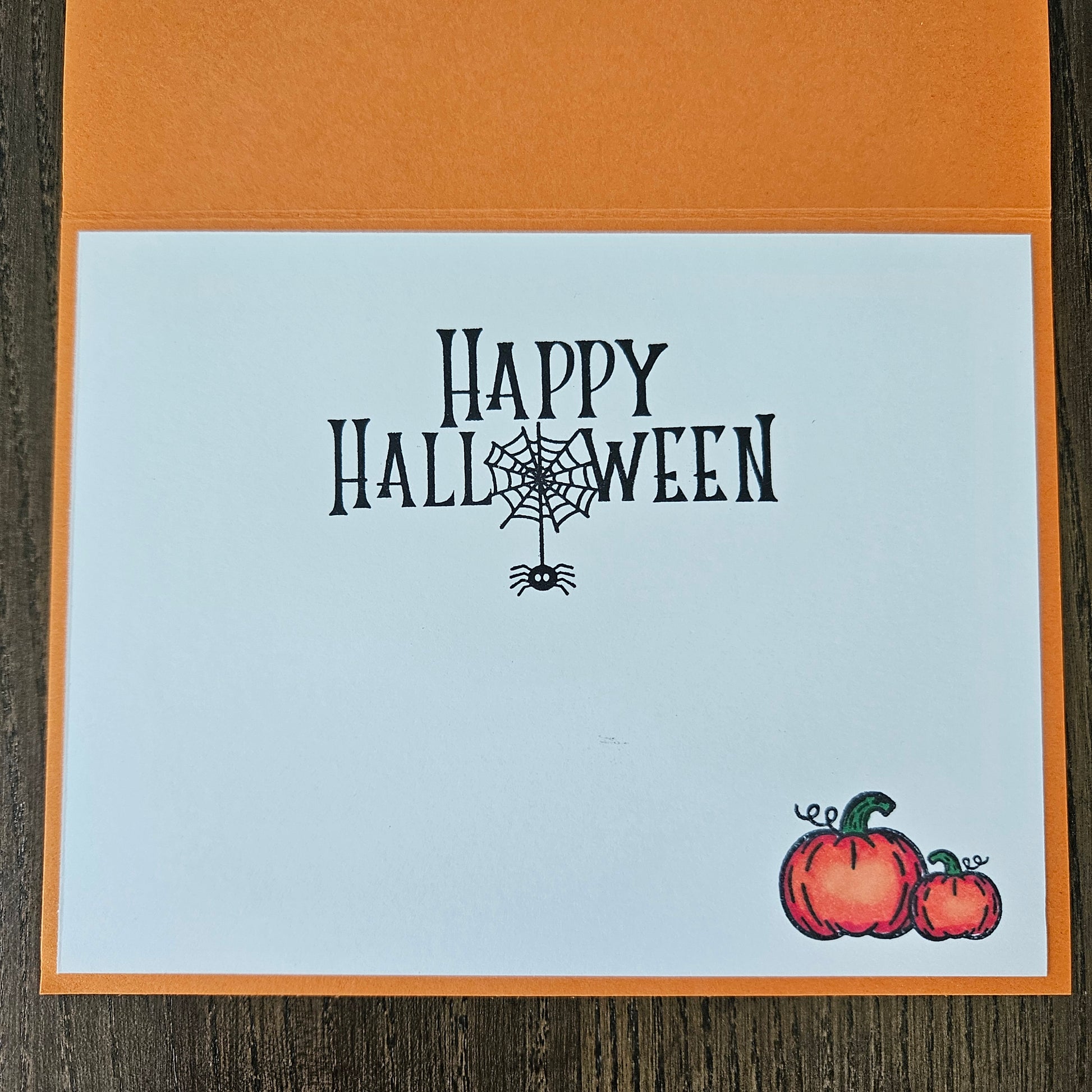 Halloween card with 'Happy Halloween' text and pumpkins on a wooden surface