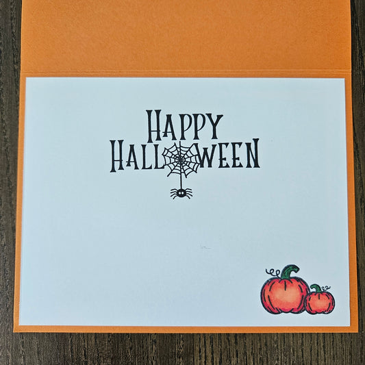 Halloween card with 'Happy Halloween' text and pumpkins on a wooden surface