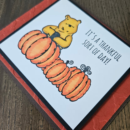 handmade horizontal A2 Thanksgiving card featuring classic Winnie the Pooh with three orange pumpkins on a white panel, an embossed textured orange mat, and a brown base, alongside views of the "HAPPY Thanksgiving" inside text 