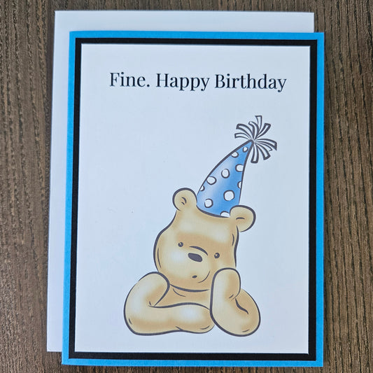 Birthday card with a bear wearing a party hat on a wooden surface