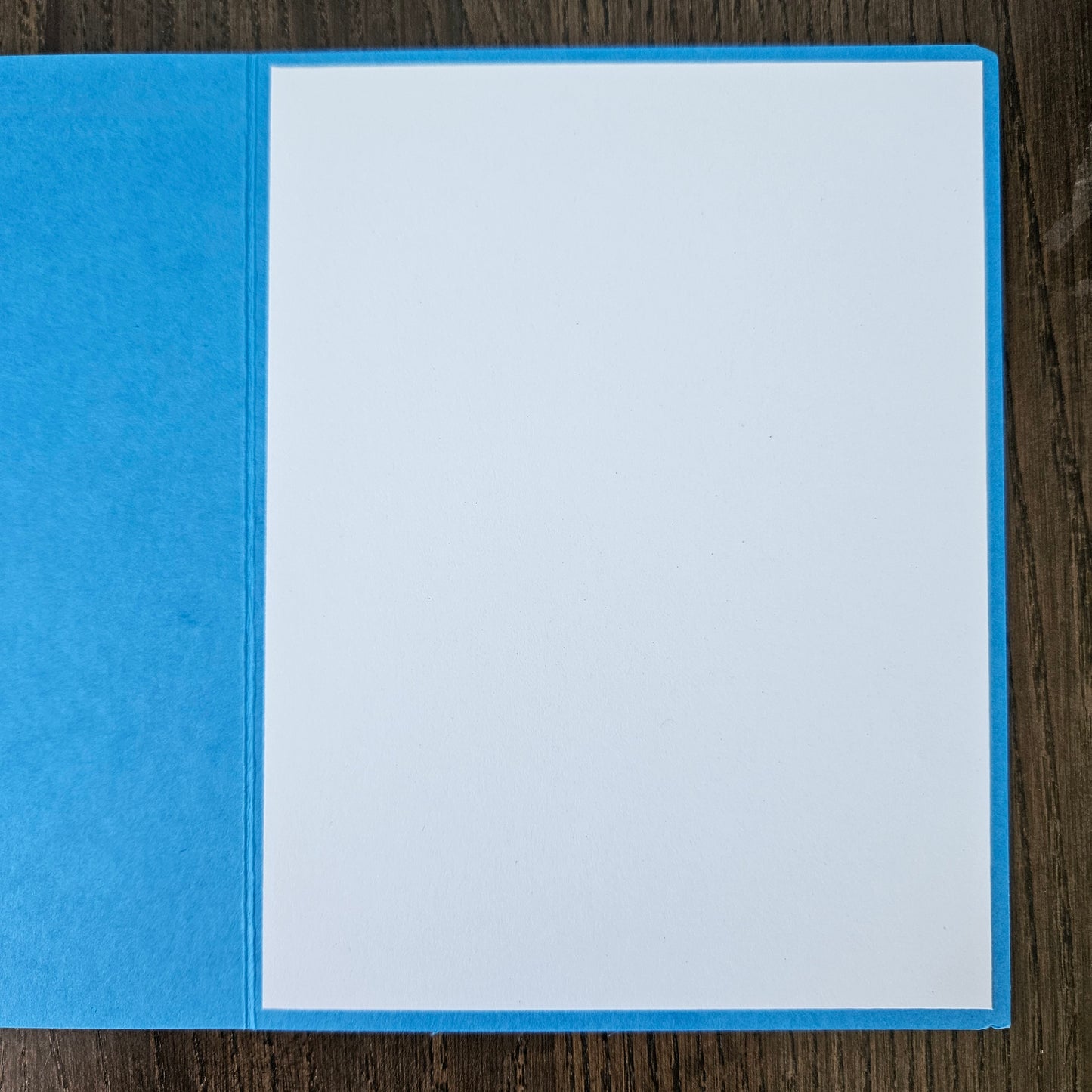 Blue card with white interior on a wooden surface