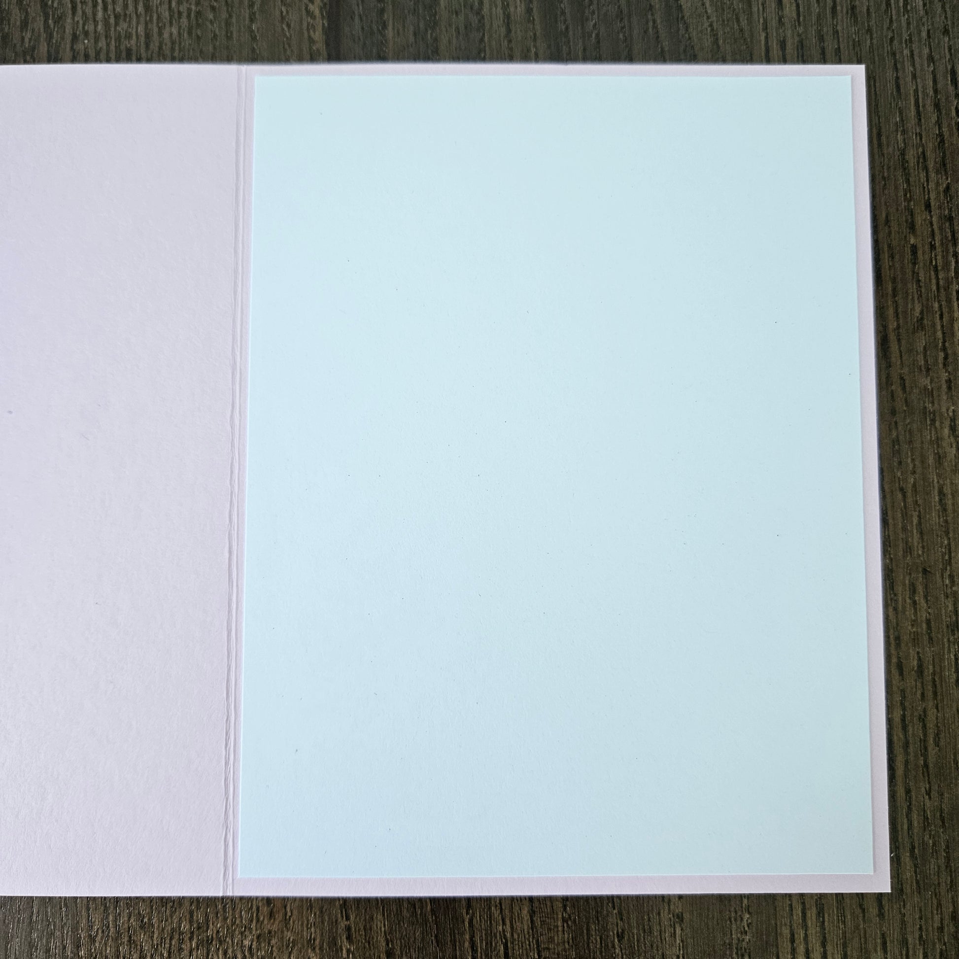 Two-tone light blue and pink card on a dark wooden surface