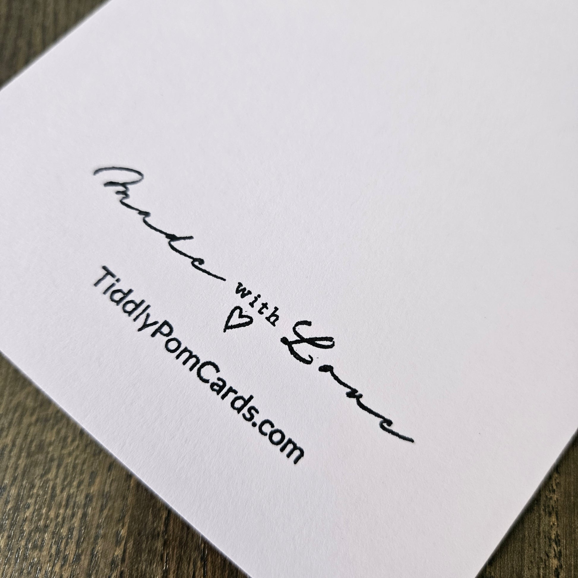 White card with black text and a heart symbol on a wooden surface