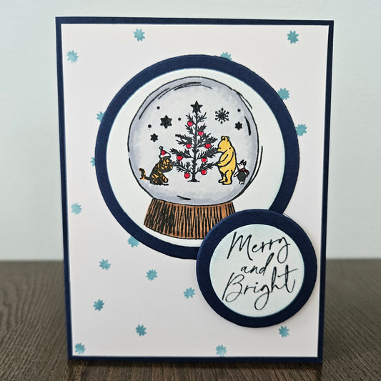 Christmas-themed card with a snow globe design featuring Winnie the Pooh and friends, on a white background.