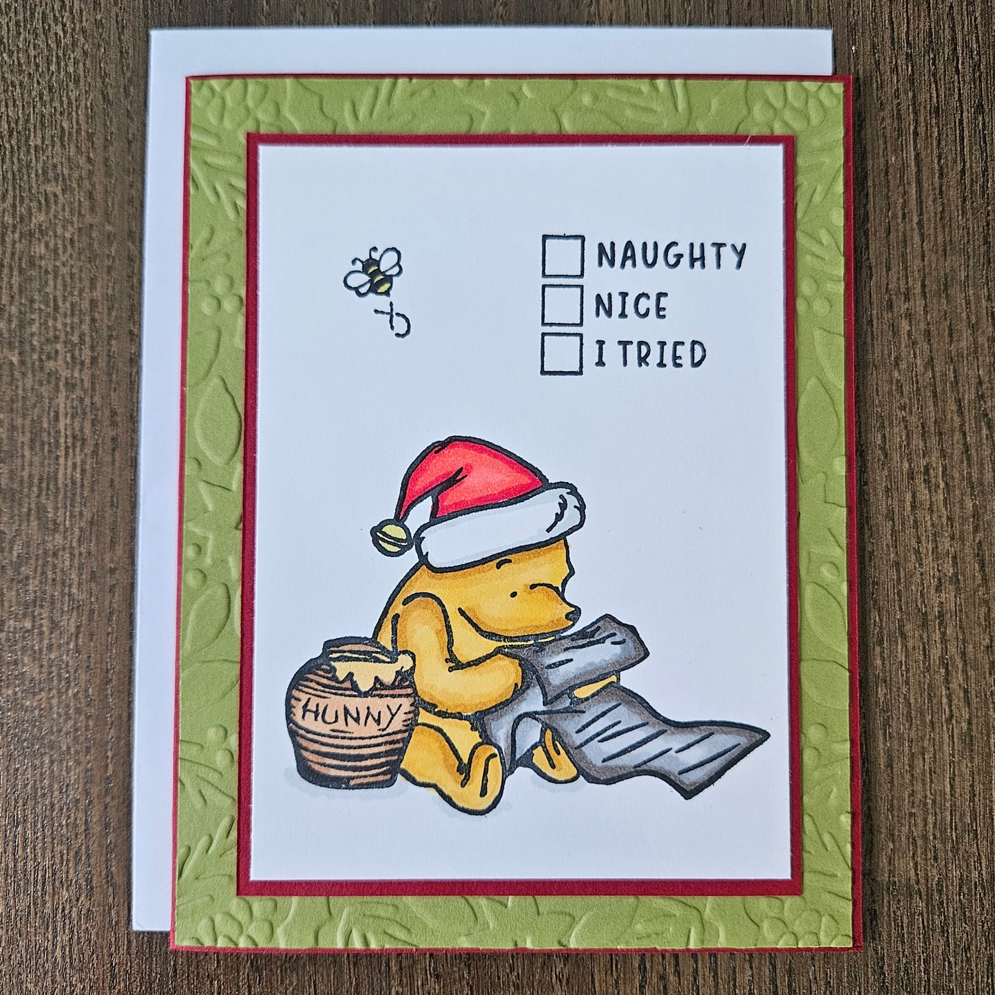 Handmade Winnie the Pooh Christmas card featuring a classic hand-colored illustration of Pooh Bear wearing a Santa hat and checking off I Tried on a Naughty or Nice checklist next to a hunny pot.