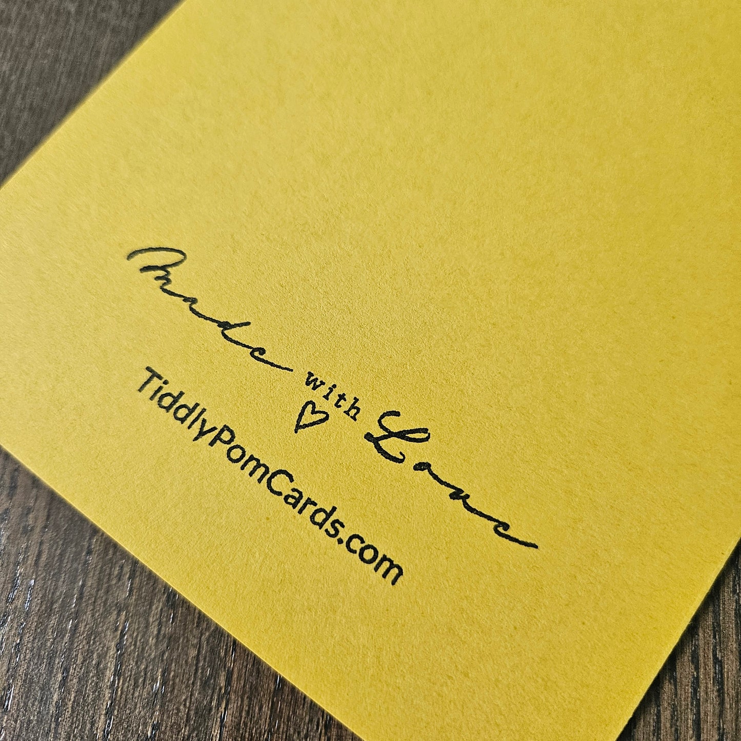 Yellow card with 'Made with Love' text and TiddlyPomCards.com on a wooden surface