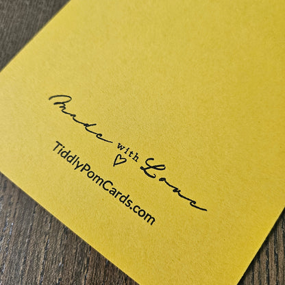 Yellow card with 'Made with Love' text and TiddlyPomCards.com on a wooden surface