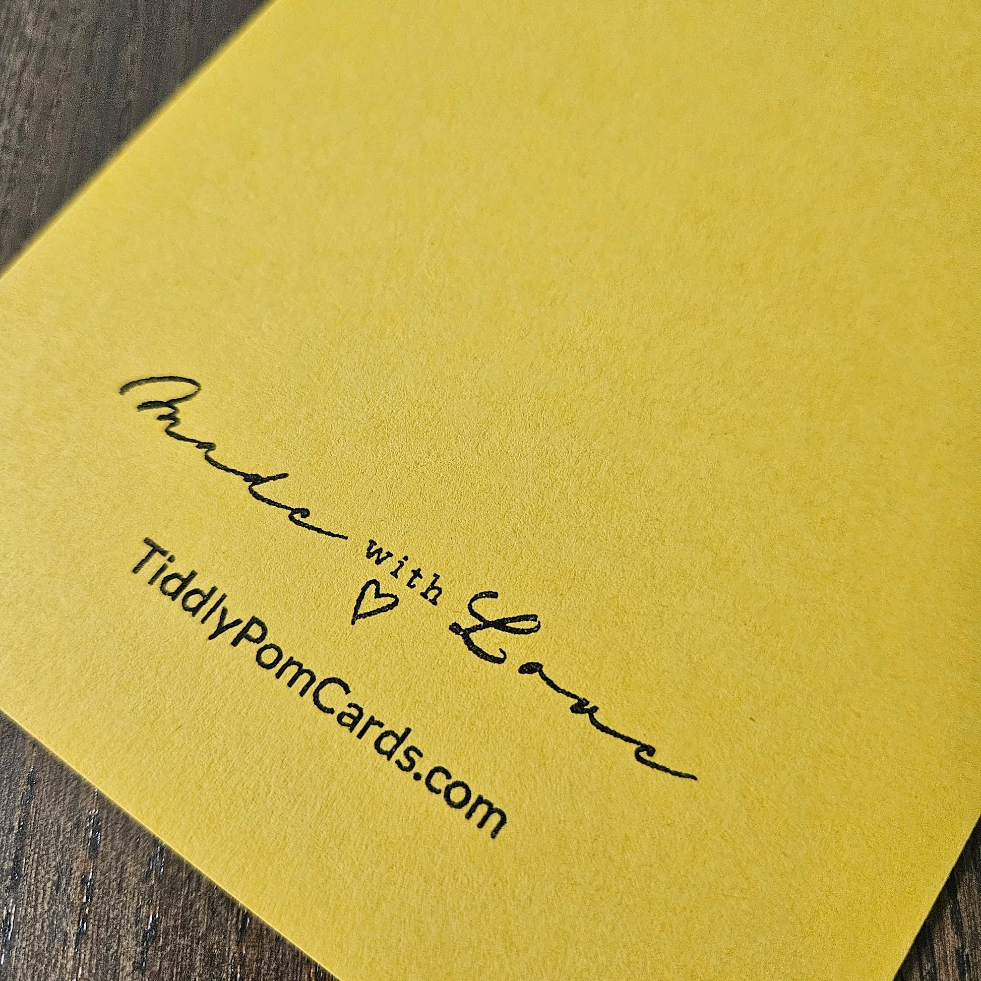 Yellow card with 'Made with Love' and 'TiddlyPomCards.com' text on a wooden surface