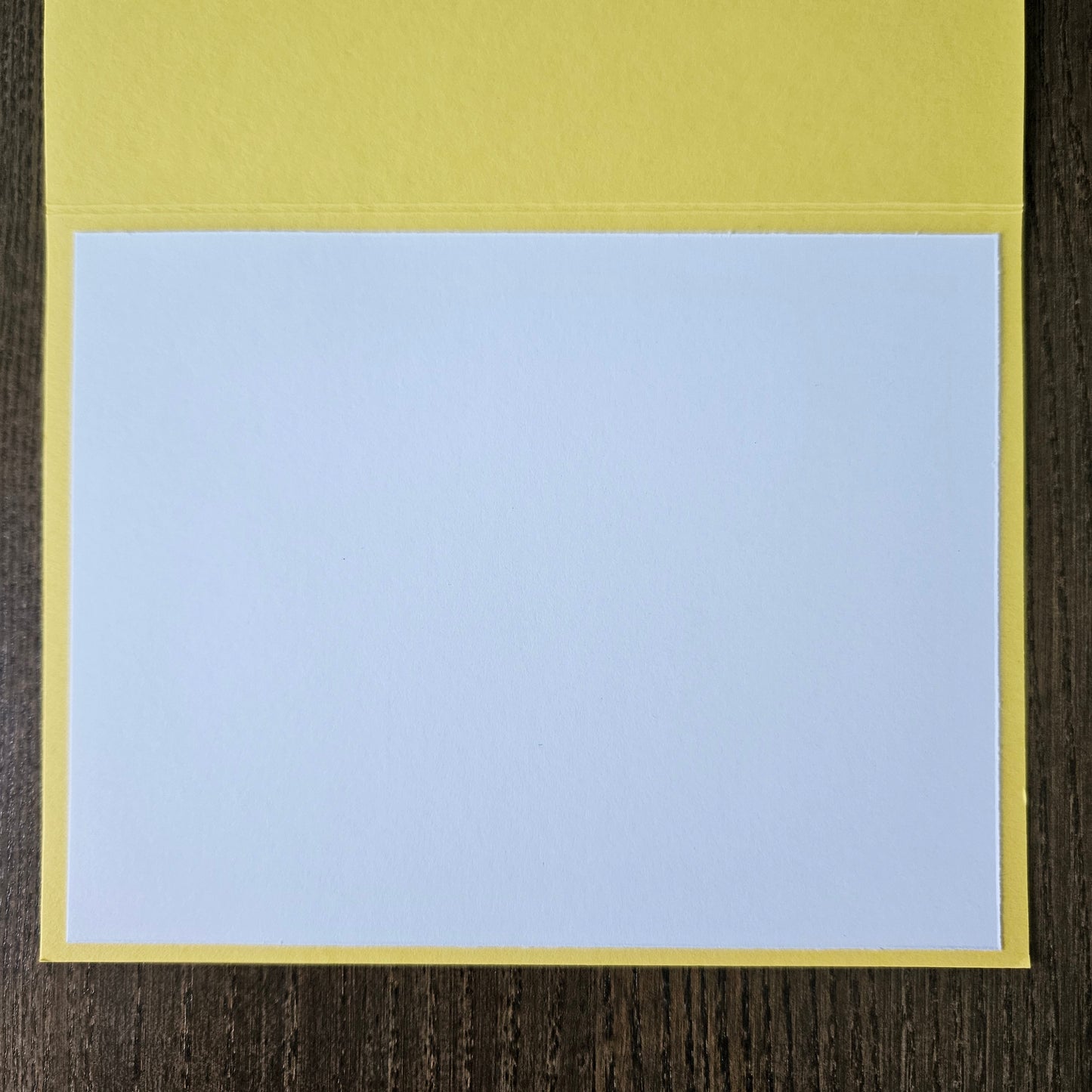 Light blue square with a yellow border on a wooden surface