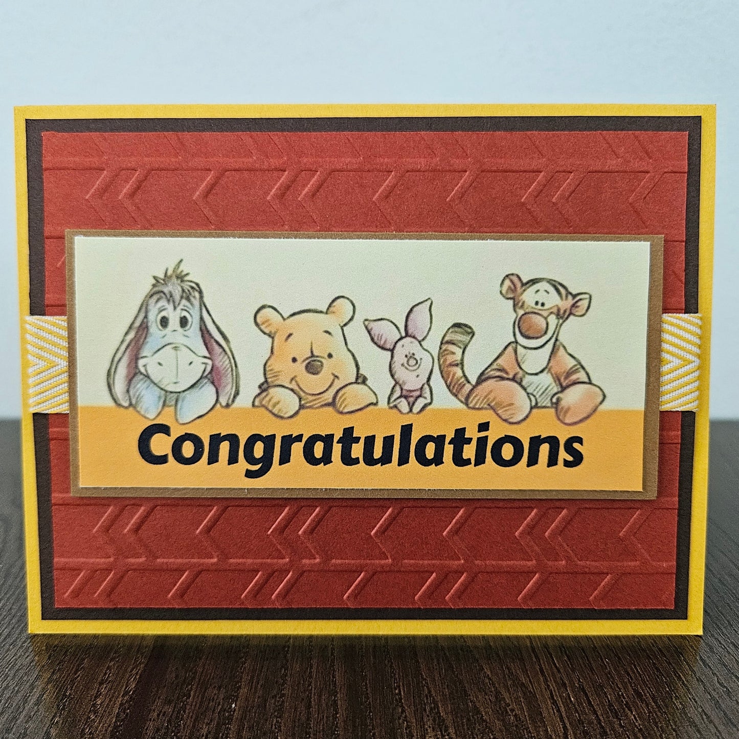 Handmade Winnie the Pooh congratulations card featuring a classic whimsical illustration of Pooh Bear and his friends celebrating a milestone, finished with layered cardstock frames and a crisp sentiment banner.