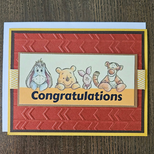 Greeting card with cartoon characters and 'Congratulations' text on a wooden surface