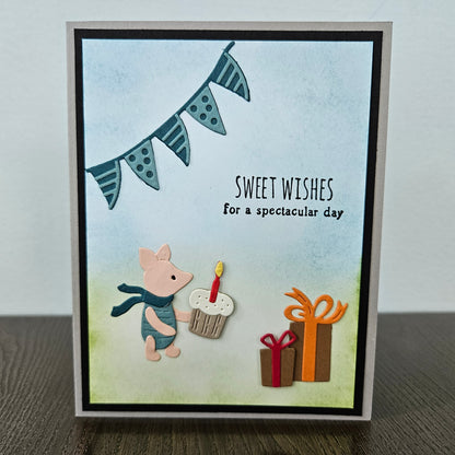 Handmade Winnie the Pooh birthday card featuring a die-cut illustration of Piglet holding a cupcake beneath a hand-colored bunting banner, with small gift boxes on a soft hand-blended layered background.