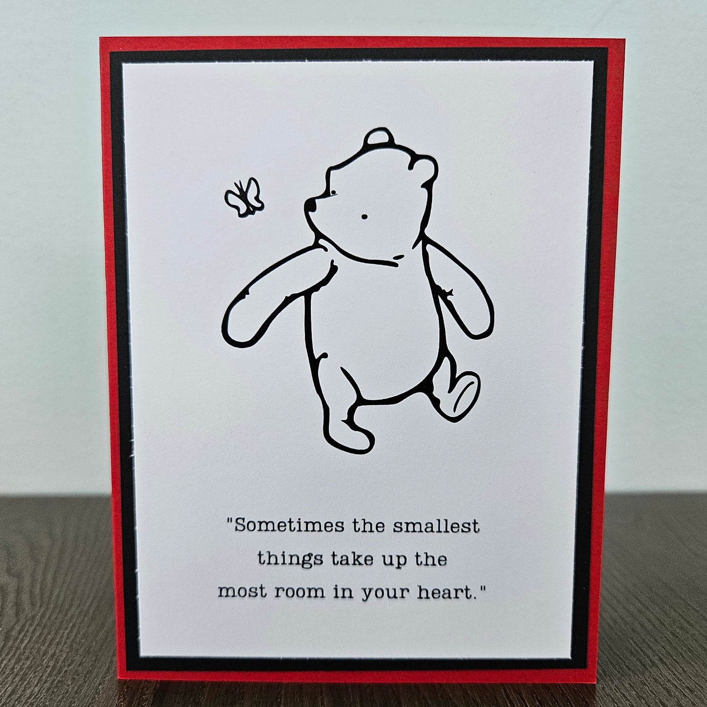 Winnie The Pooh Card with a black and white illustration of a bear and a butterfly, with text on a white background.