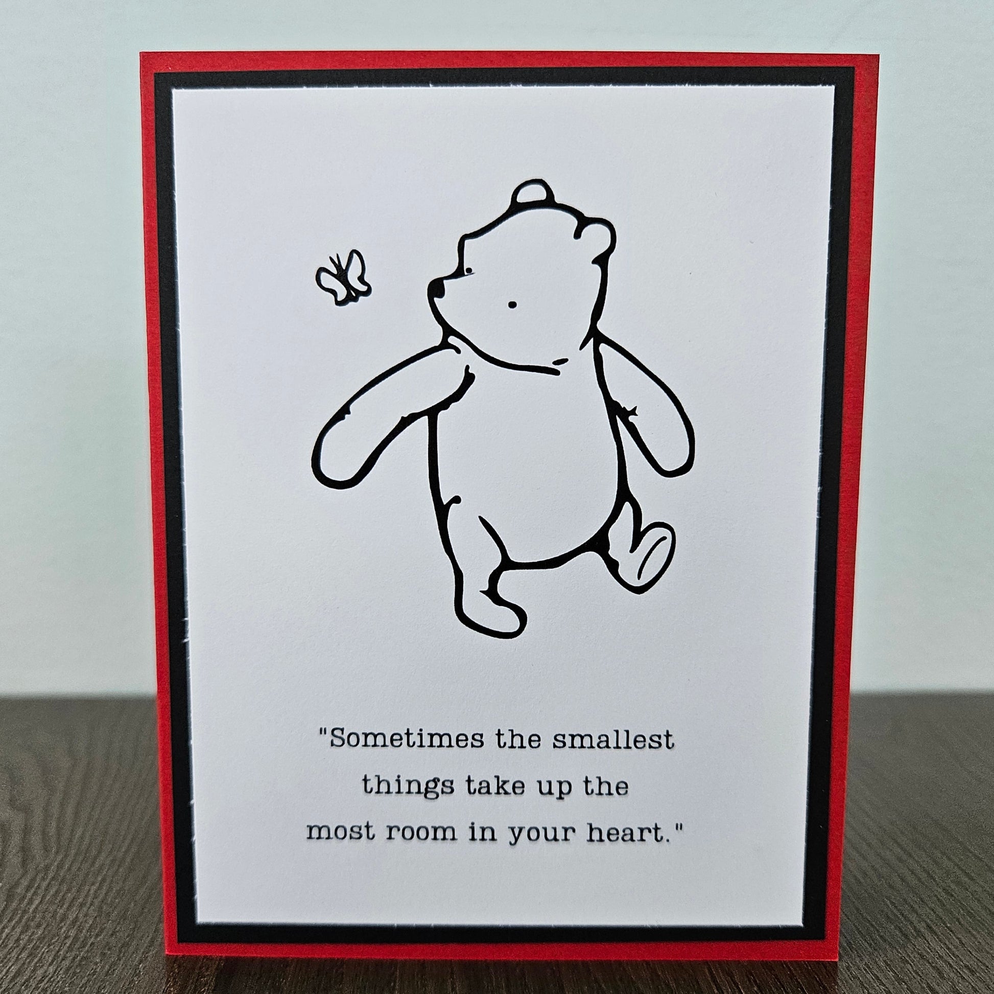 Winnie The Pooh Card with a black and white illustration of a bear and a butterfly, with text on a white background.