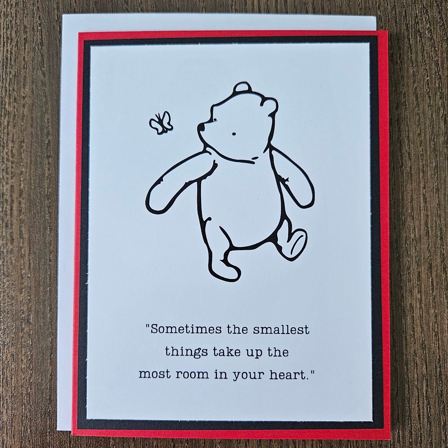 Card with a bear illustration and text on a wooden surface