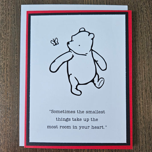 Card with a bear illustration and text on a wooden surface
