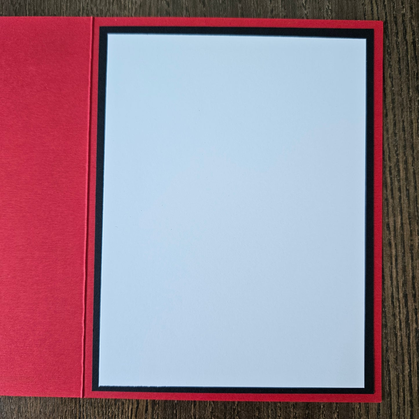 Red card with a white card inside on a wooden surface