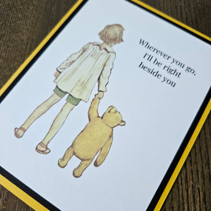 Card with illustration of a child and bear holding hands and text on a wooden surface