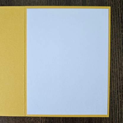 Two-toned card with light blue top and yellow bottom on a wooden surface