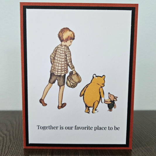 Handmade friendship card featuring a classic illustration of Christopher Robin, Winnie the Pooh, and Piglet walking together, framed by black and rust-red layered cardstock. Text reads Together is our favorite place to be.