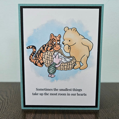 Handmade Winnie the Pooh new baby card featuring a classic watercolor illustration of Pooh, Tigger, and Piglet gathered around a basket, accented by a soft teal layered border.