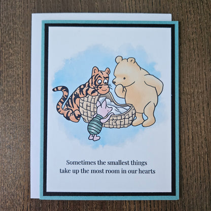 Handmade Winnie the Pooh new baby card featuring a classic watercolor illustration of Pooh, Tigger, and Piglet gathered around a basket, accented by a soft teal layered border.