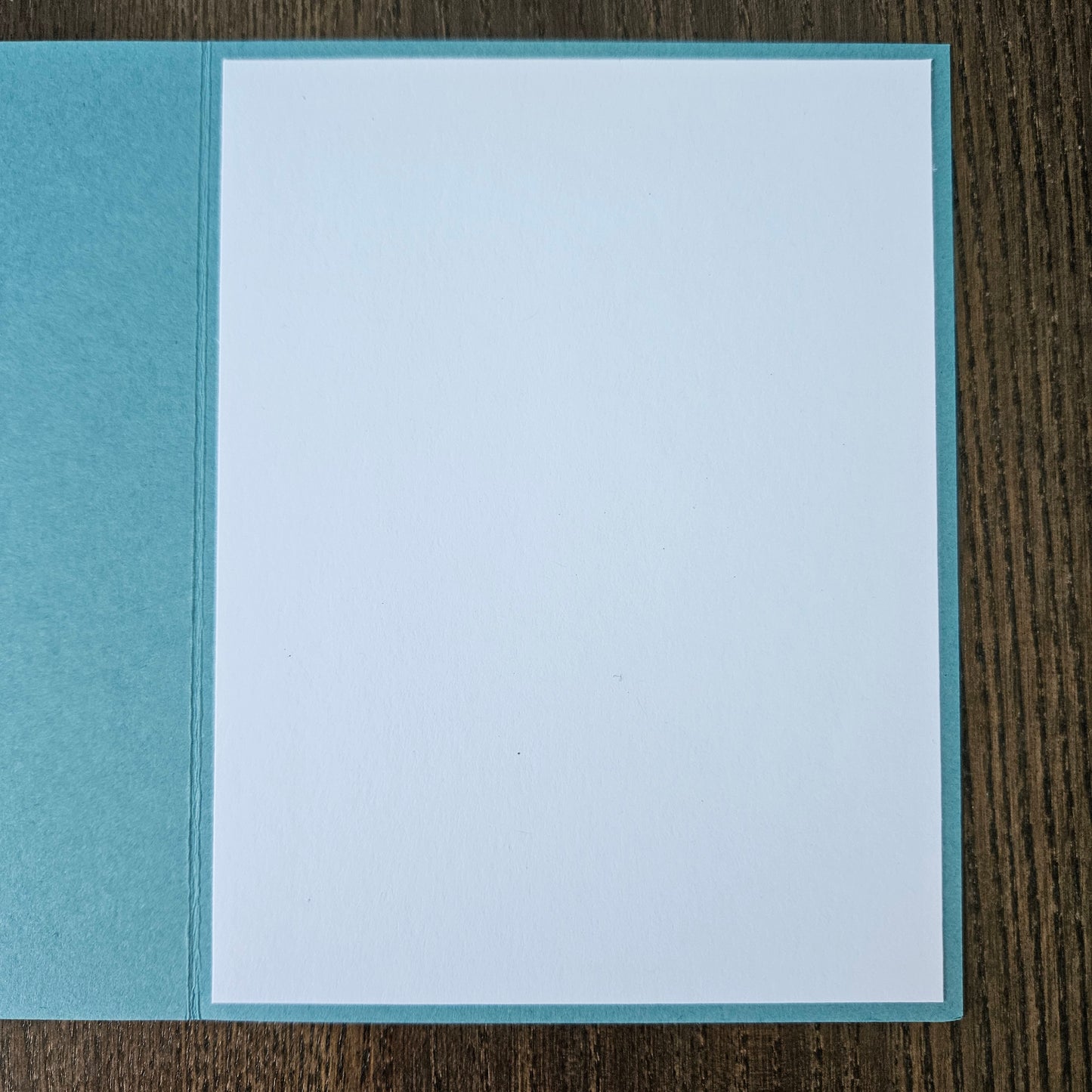 Two-toned blue card with a white center on a wooden surface