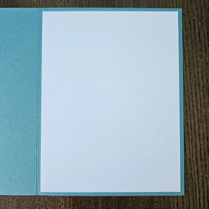 Two-toned blue card with a white center on a wooden surface