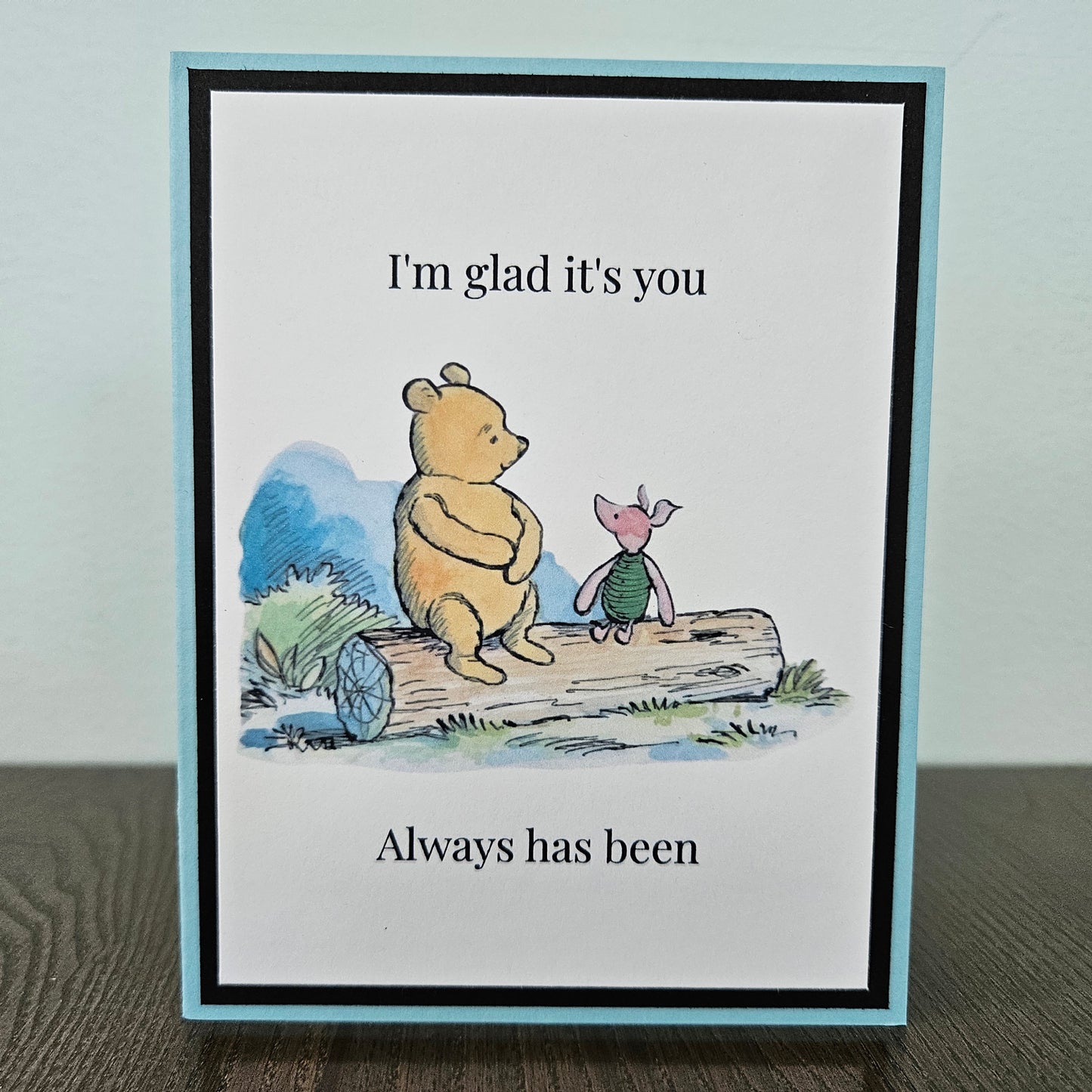 Handmade Winnie the Pooh friendship card featuring a classic watercolor illustration of Pooh and Piglet sitting side by side on a log, accented by a soft sky-blue layered border.