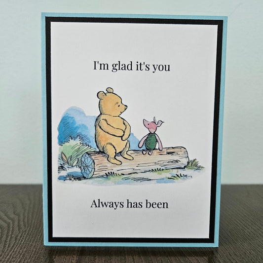 Handmade Winnie the Pooh friendship card featuring a classic watercolor illustration of Pooh and Piglet sitting side by side on a log, accented by a soft sky-blue layered border.