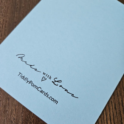 Light blue card with 'Made with Love' and 'TiddlyPomCards.com' text on a wooden surface