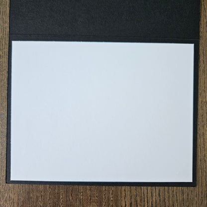 White sheet of paper in a black folder on a wooden surface